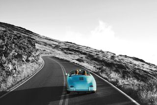 Ein blaues Cabriolet fährt eine Bergstraße entlang