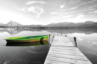 Ein grünes Ruderboot liegt am Steg eines Bergsees
