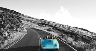 Ein blaues Cabriolet fährt eine Bergstraße entlang