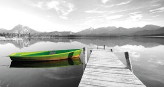 Ein grünes Ruderboot liegt am Steg eines Bergsees